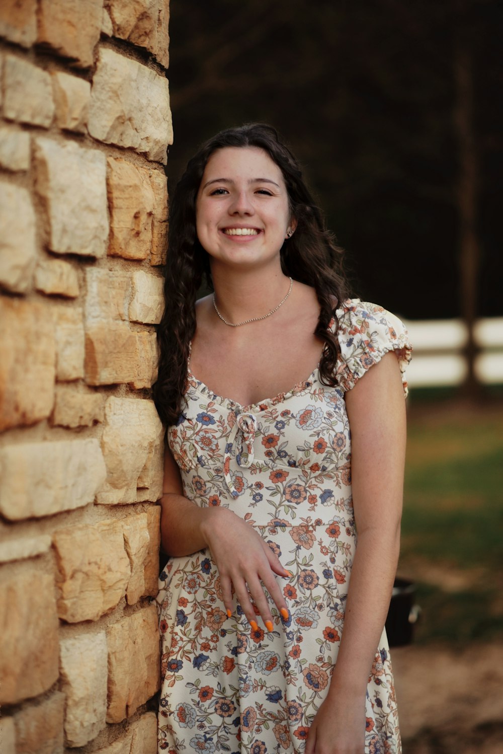 a person smiling in front of a stone wall