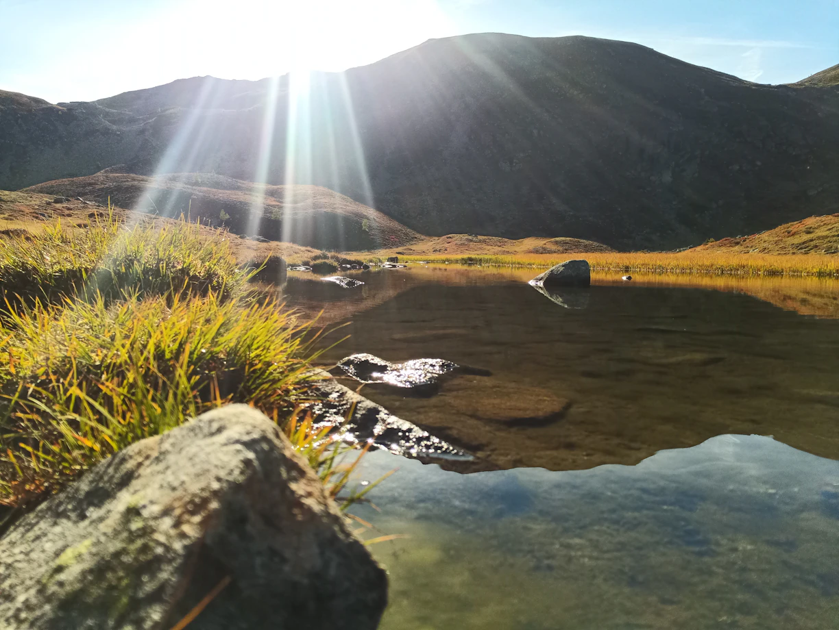 a body of water with a waterfall and grass on the side
