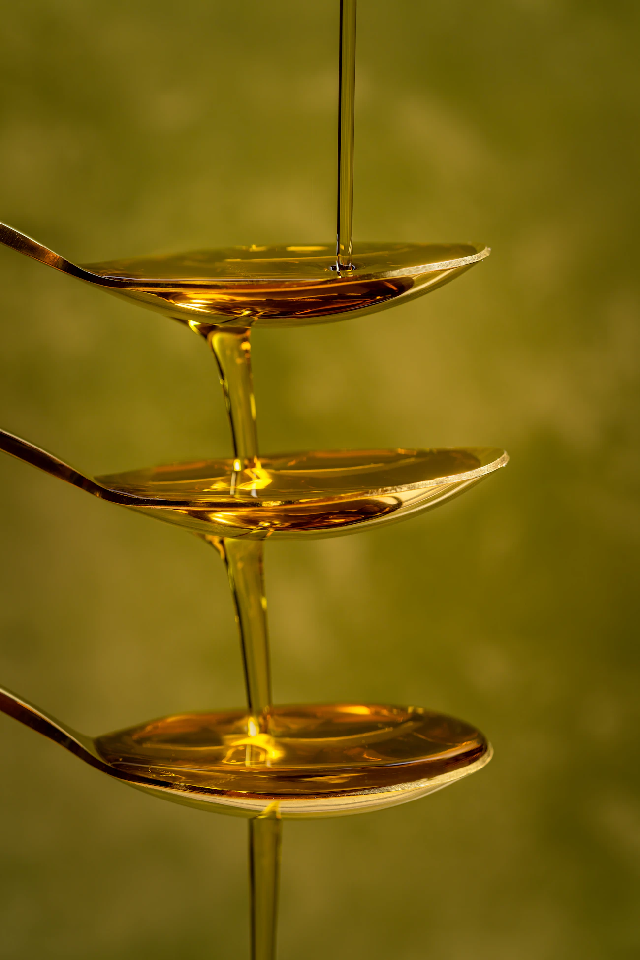 Golden olive oil pouring onto a spoon