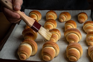 a person holding a pair of wooden spoons over a pile of pretzels