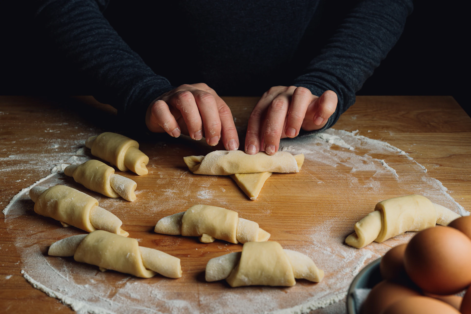 A baker's hands skillfully shaping croissant dough in a bright, inviting kitchen setting.