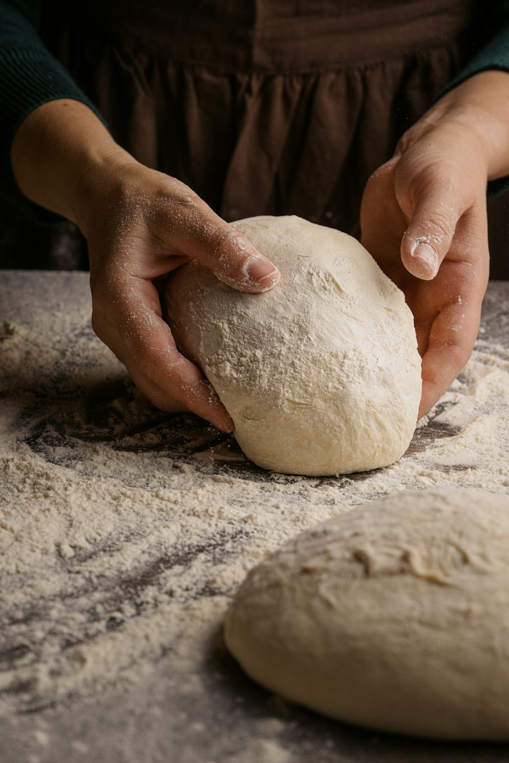 a person kneading a ball of dough on top of a table