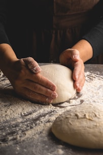 Close-up of hands shaping dough with natural light highlighting the texture and simplicity.