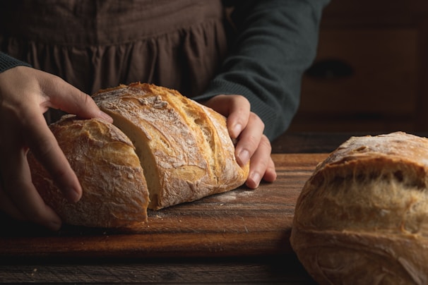 A baker carefully slicing a warm, crusty baguette with a serrated knife.