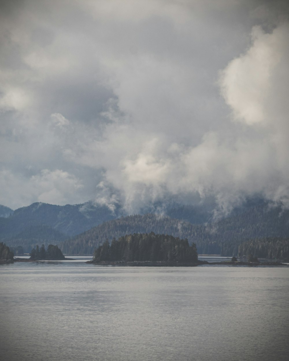 a body of water with trees and mountains in the background