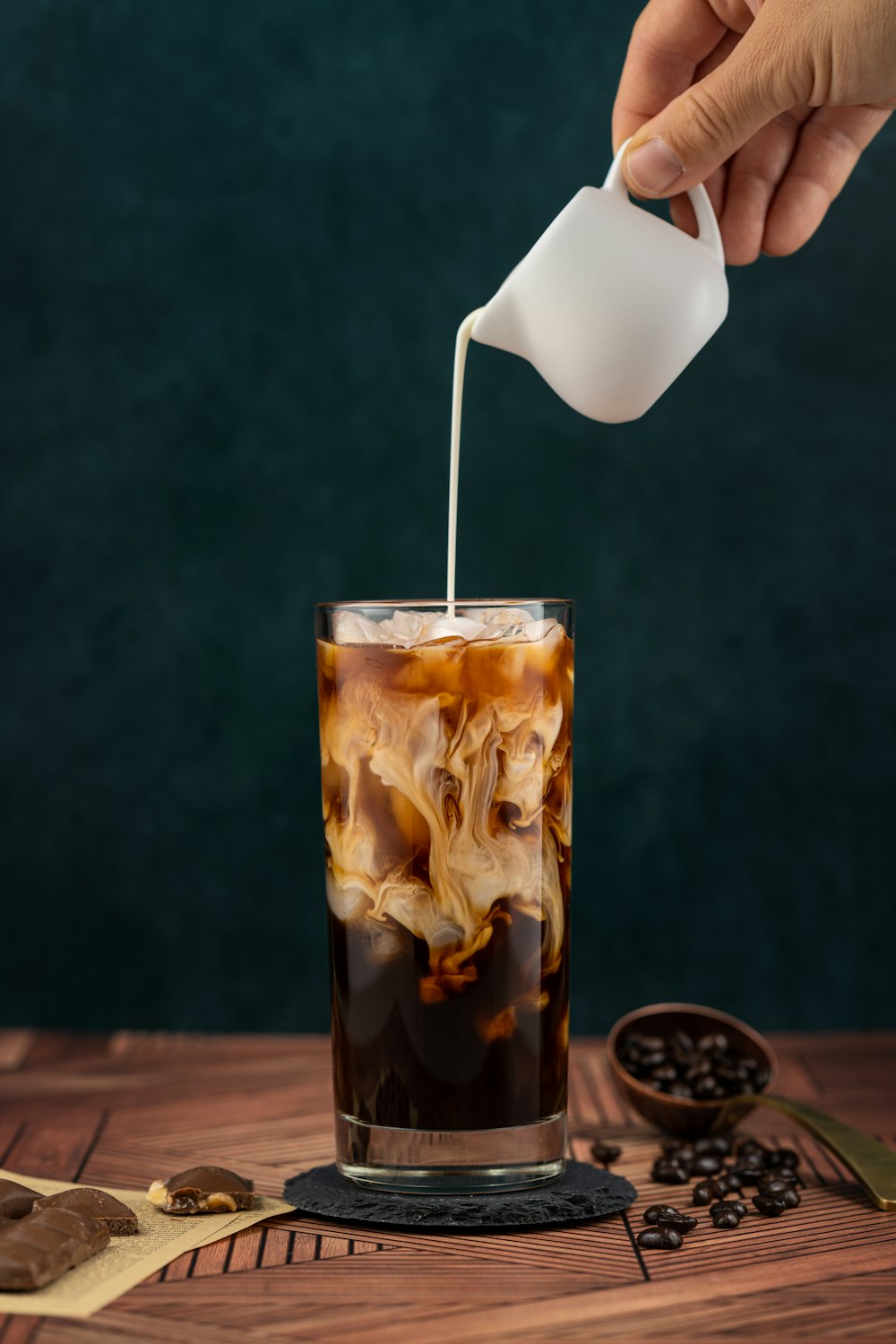 a hand pouring a liquid into a glass with a spoon