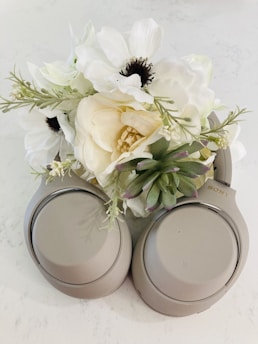 A close-up of headphones resting on a surfboard with tropical flowers nearby.