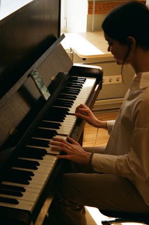 Portrait of Ethan Wood carefully tuning a grand piano in a softly lit music studio.