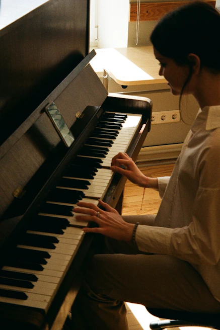 A young girl playing piano with focused joy, her fingers dancing over the keys in a sunlit room.
