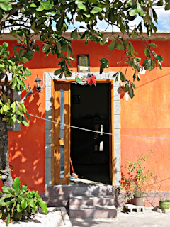 Door adorned with a white and red capa de porta featuring delicate candomblé patterns.