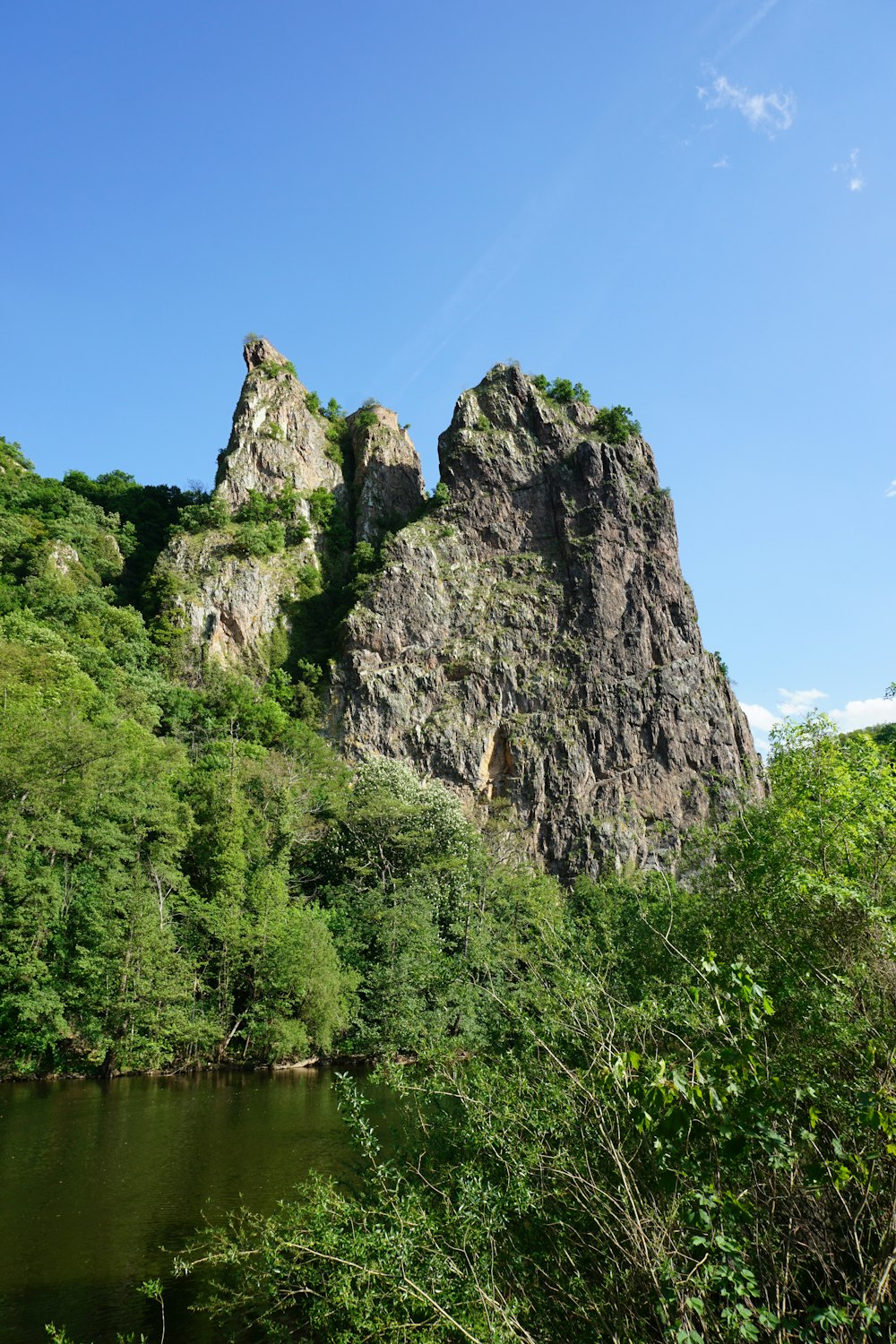 a rocky cliff with trees and water below