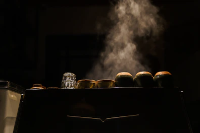 A set of double glass cups with steam rising, placed on a cream-colored wooden table.