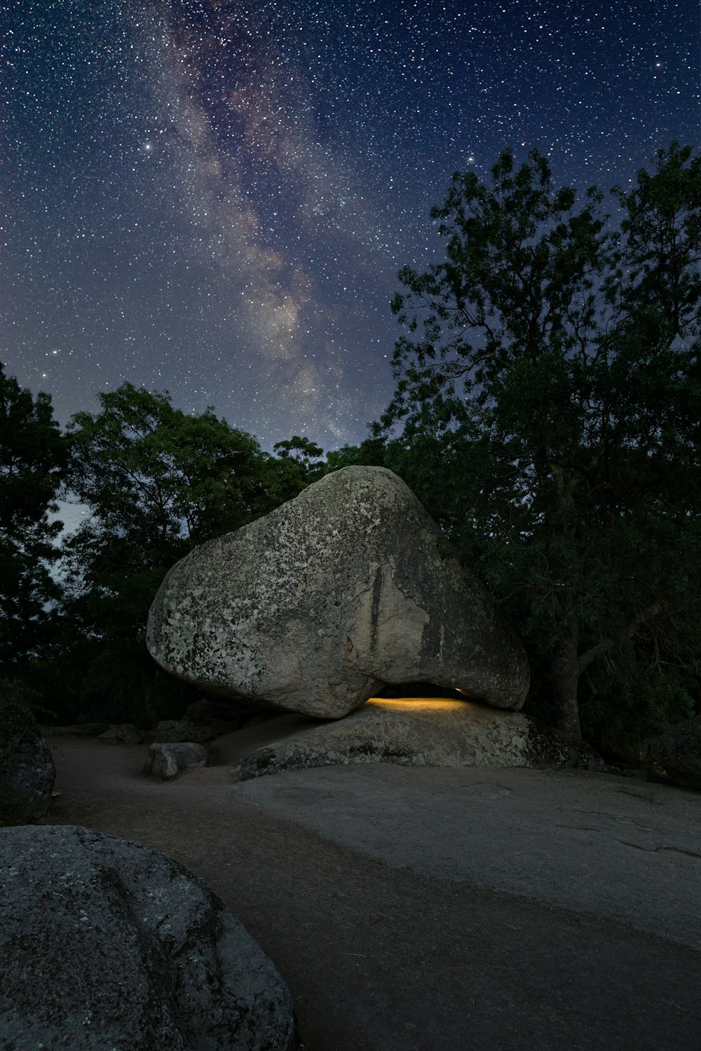 a large rock with trees in the background