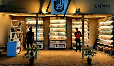 a couple of people standing in front of a store with shelves of books