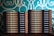 Two stacks of books are arranged, each book with a title that reads 'Team Lead Succeed.' The author's name, Nick Fewings, is visible on the spines. The books are neatly placed on a wooden surface, in front of a decorative background with intricate teal and cream patterns.