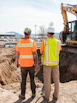 men in safety vests standing in front of a construction vehicle