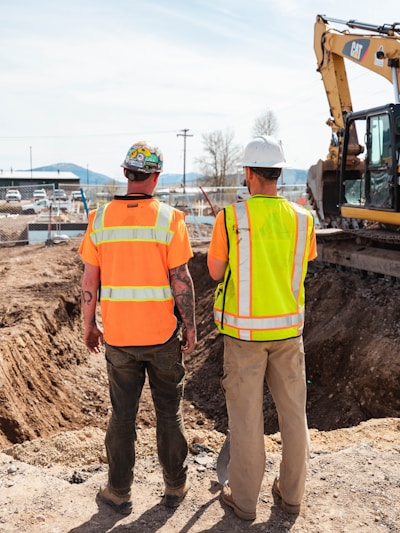 men in safety vests standing in front of a construction vehicle