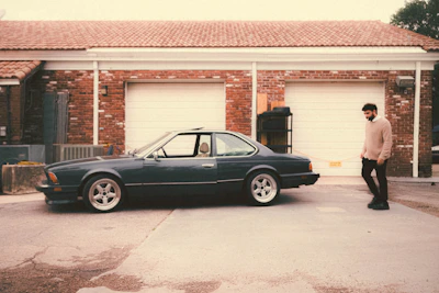 A beautifully restored vintage classic car parked in front of a rustic garage.