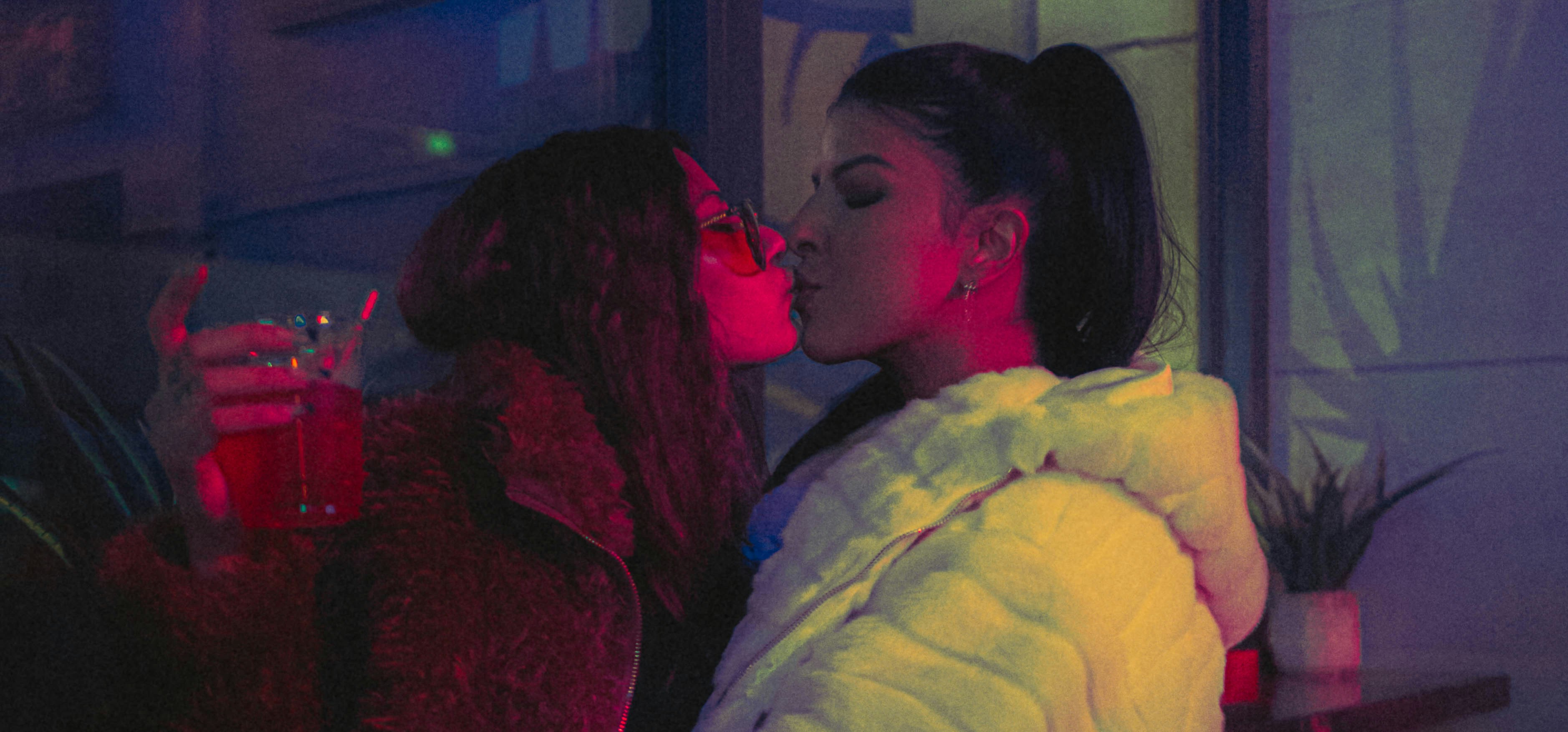 a person kissing another woman