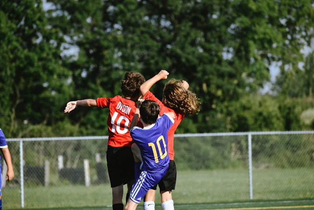 A group of boys playing football on a sunny field