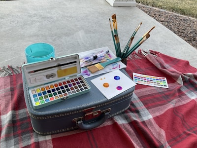 A cozy setup with brushes, canvas and a refreshing drink on the side.