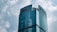 A modern skyscraper with a curved glass facade, prominently displaying the HNA logo at the top. The building rises against a backdrop of a cloudy sky, showcasing a blend of architectural innovation and corporate branding.