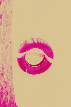 A stylized image featuring a circular tire with visible tread patterns in a vivid magenta hue against a pale yellow background. The left side shows a textured vertical surface that is similarly colored.