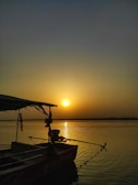 Traditional Cambodian boat floating on a calm river at sunset.