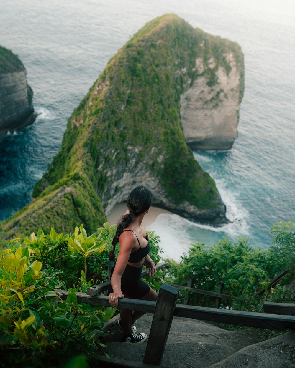 a person sitting on a bench looking at the ocean