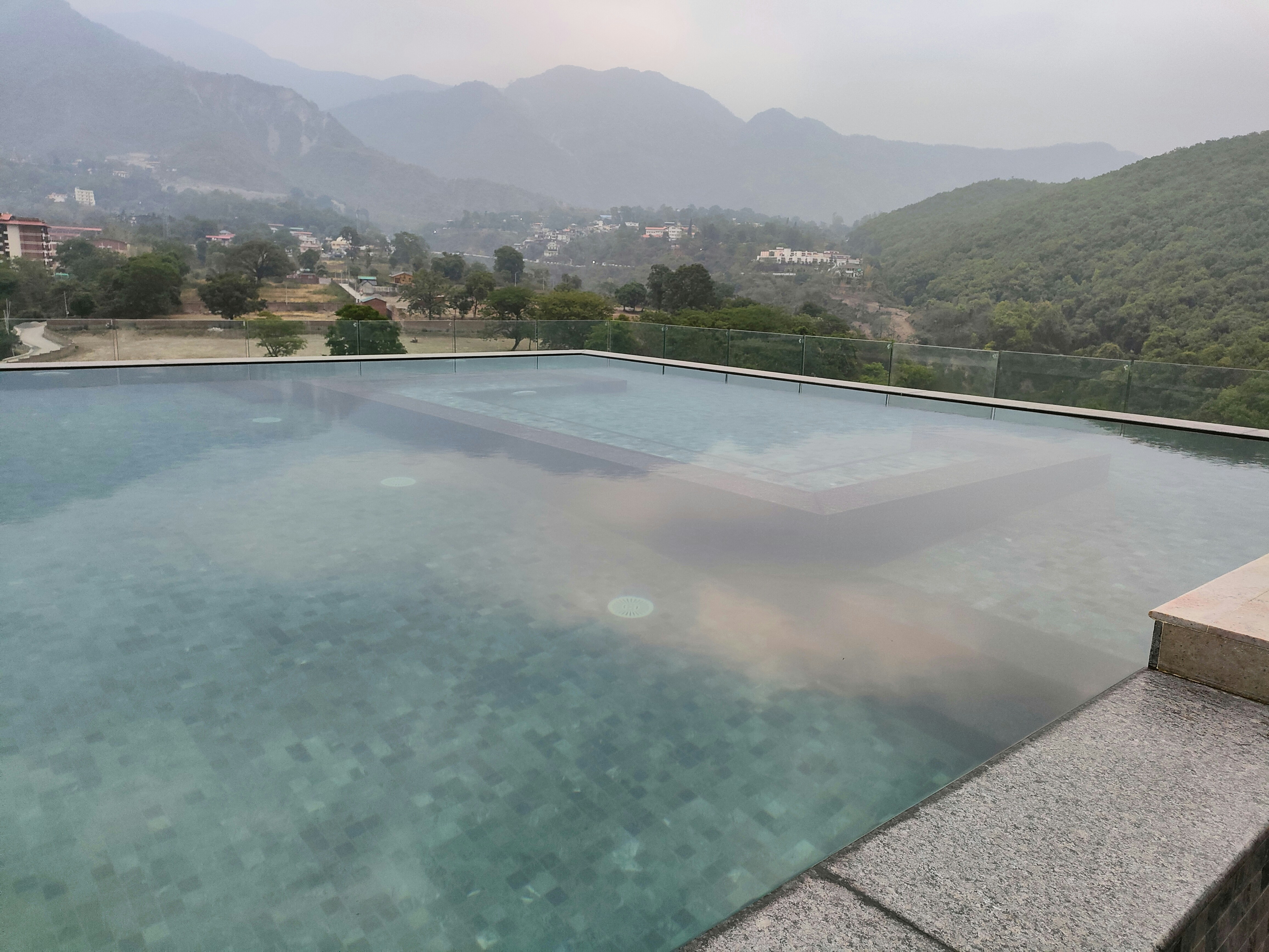 Private villa with infinity pool overlooking misty volcanic landscape, dark stone architecture, evening atmospheric lighting