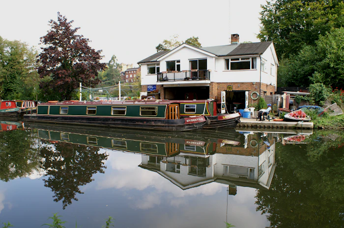 A white house on posts beside calm water with trees on the far bank