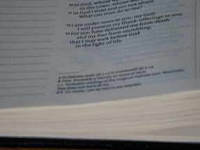 A close-up view of an open book showing printed text on the pages. The text is primarily in black ink and includes headings and footnotes. The image captures the texture of the pages and the layout of the printed lines.
