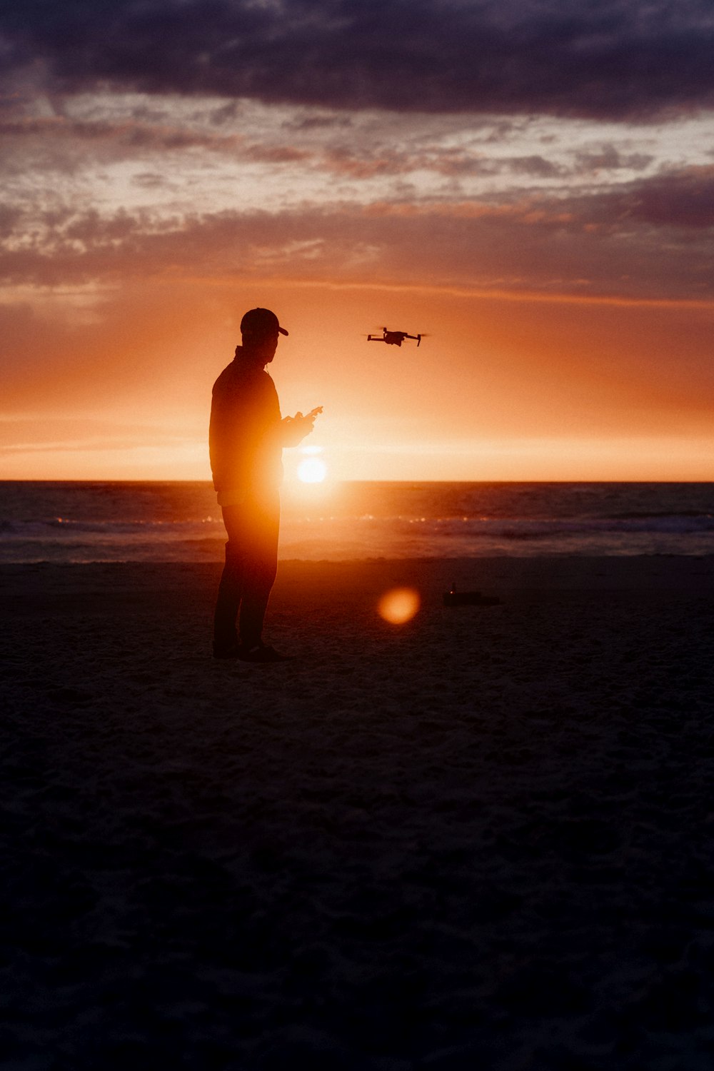 a person standing on a beach with a plane flying in the sky