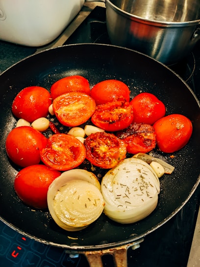 A close-up of a gleaming stainless steel skillet with fresh vegetables sizzling inside.