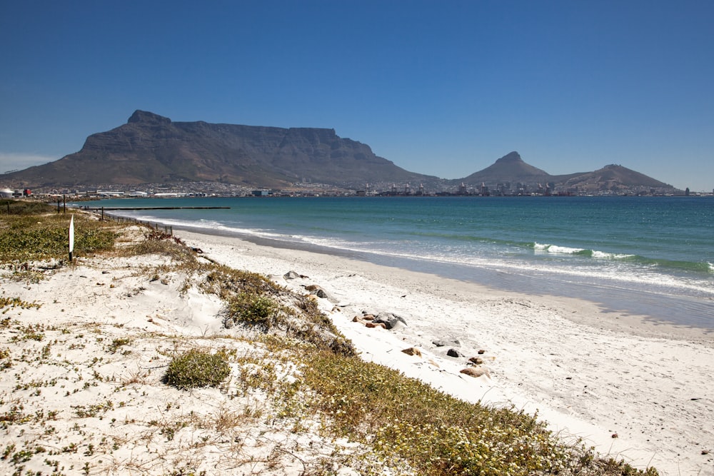 a beach with a body of water and mountains in the background