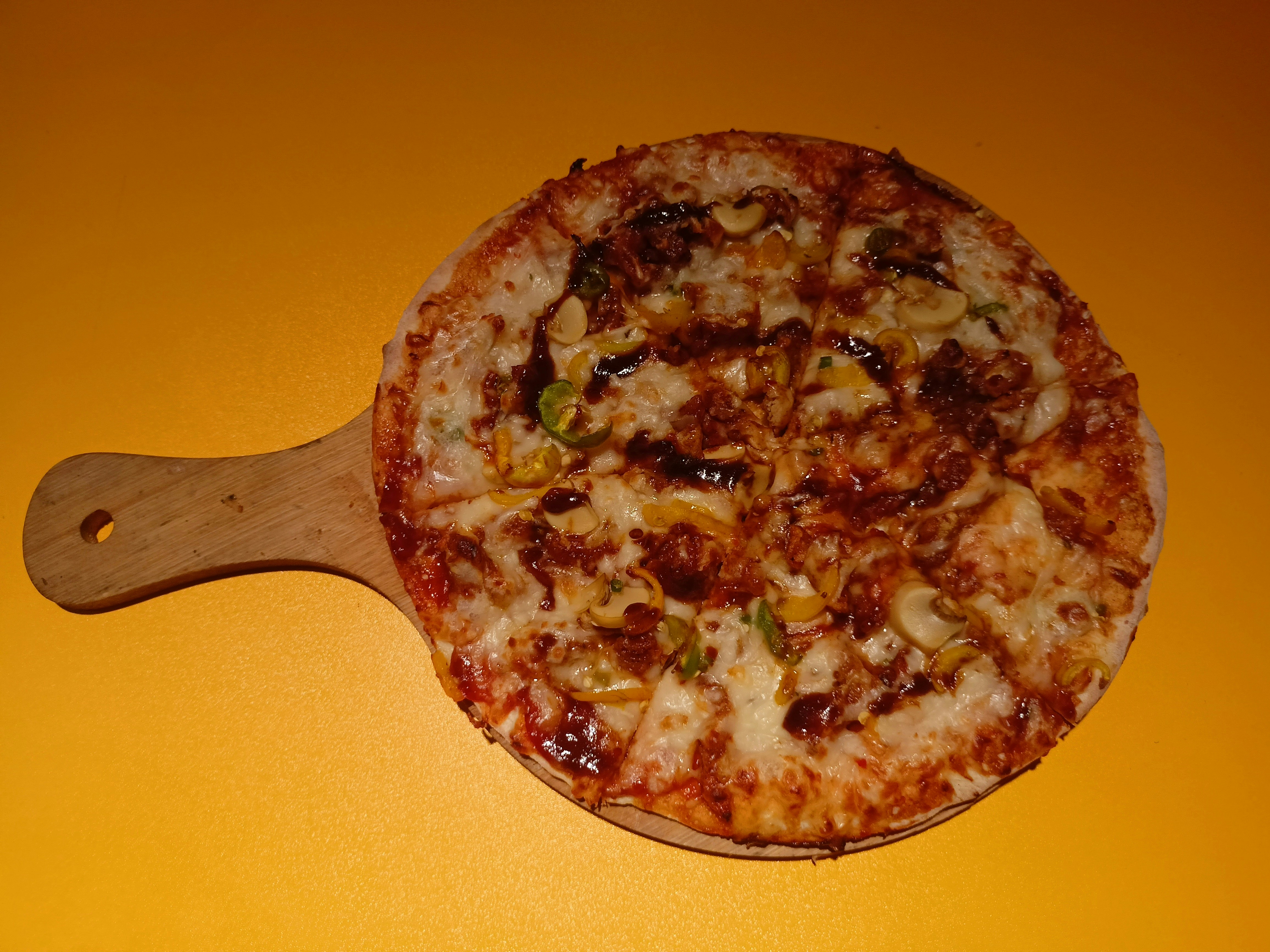 Pizza with vibrant toppings overhead, melted cheese, colorful vegetables, rustic wooden board