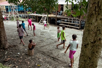 Children playing traditional bamboo stilts (egrang) in a village setting.