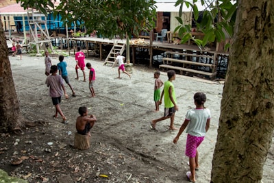 Children playing traditional bamboo stilts (egrang) in a village setting.