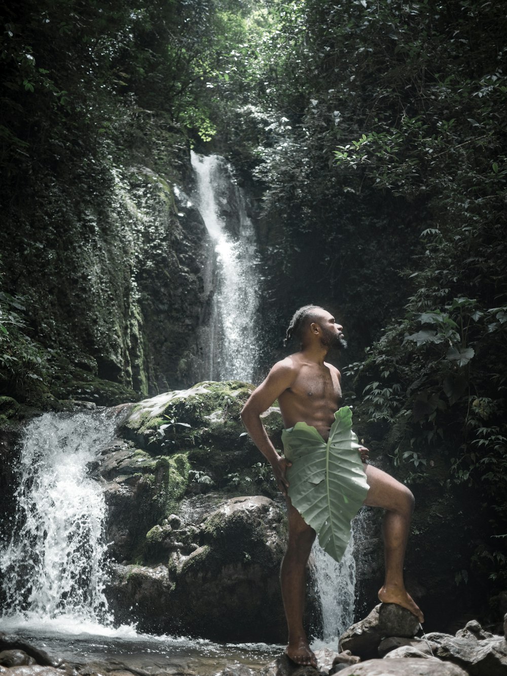 um homem de pé em uma rocha perto de uma cachoeira