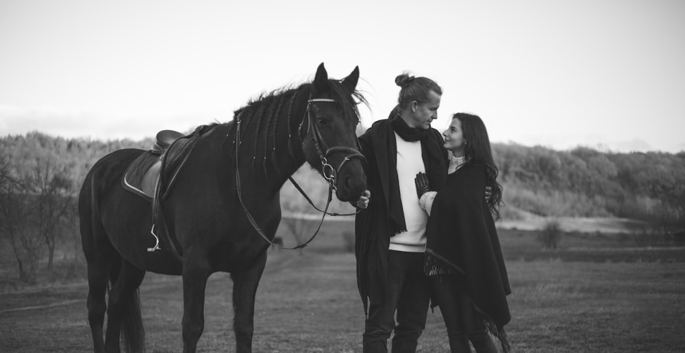 a man and woman standing next to a horse