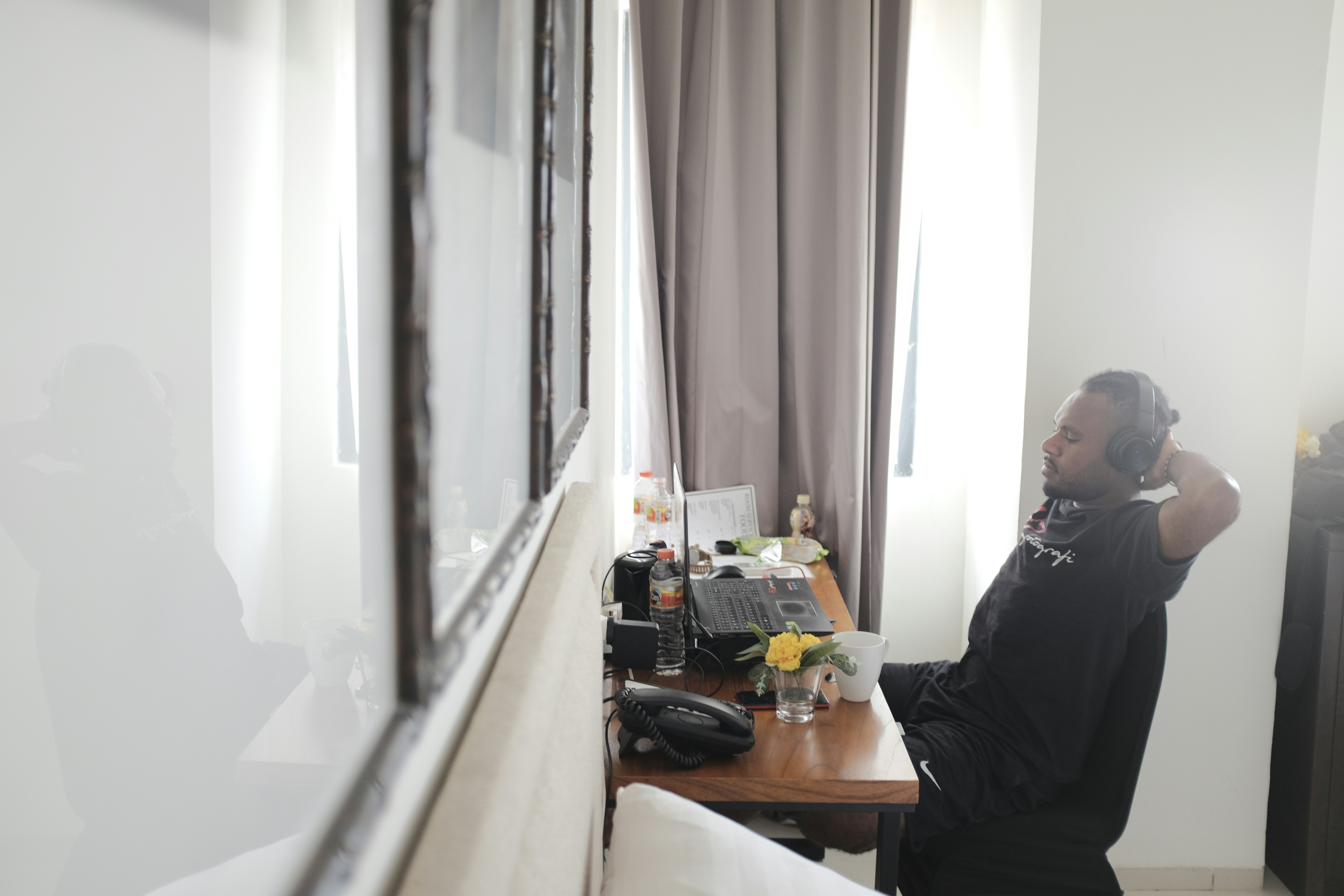 a person with headphones on in front of a desk with a computer