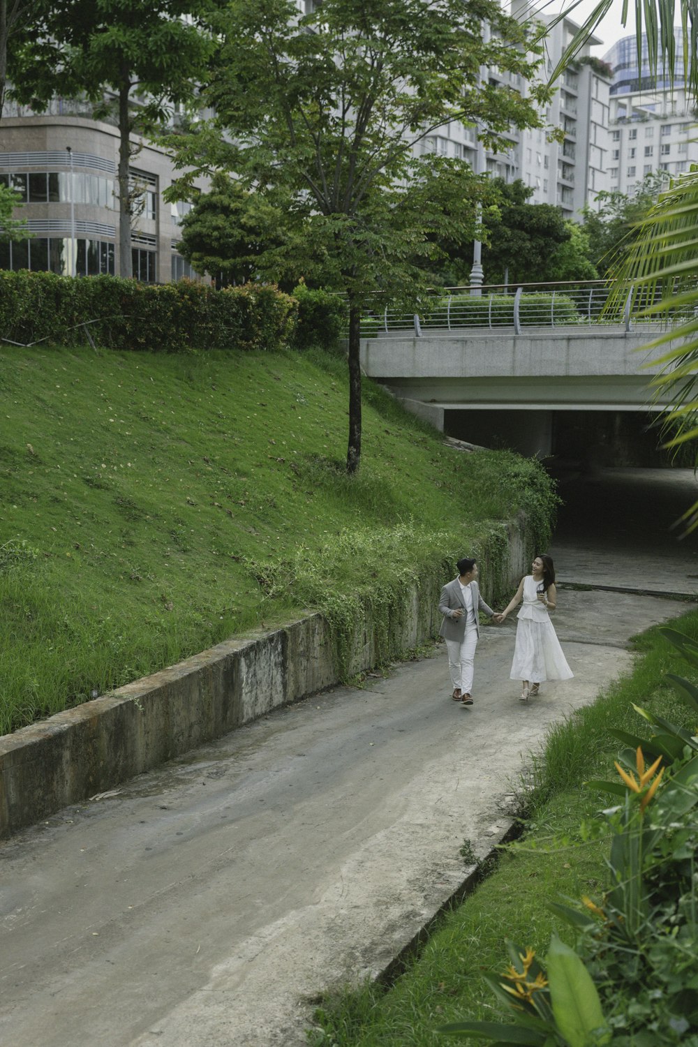 a man and woman walking down a path in a park