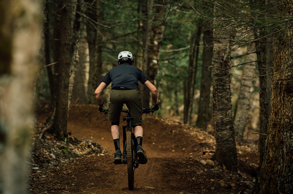 Un hombre montando en bicicleta por un camino de tierra en un bosque