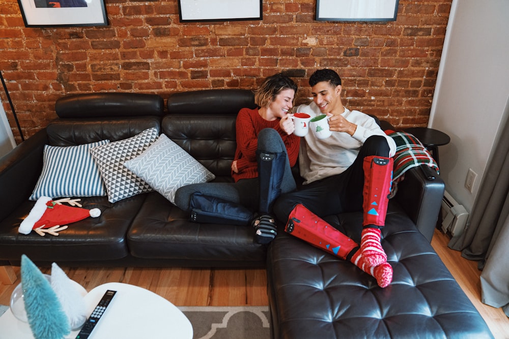 a man and a woman sitting on a couch with a santa clause garment