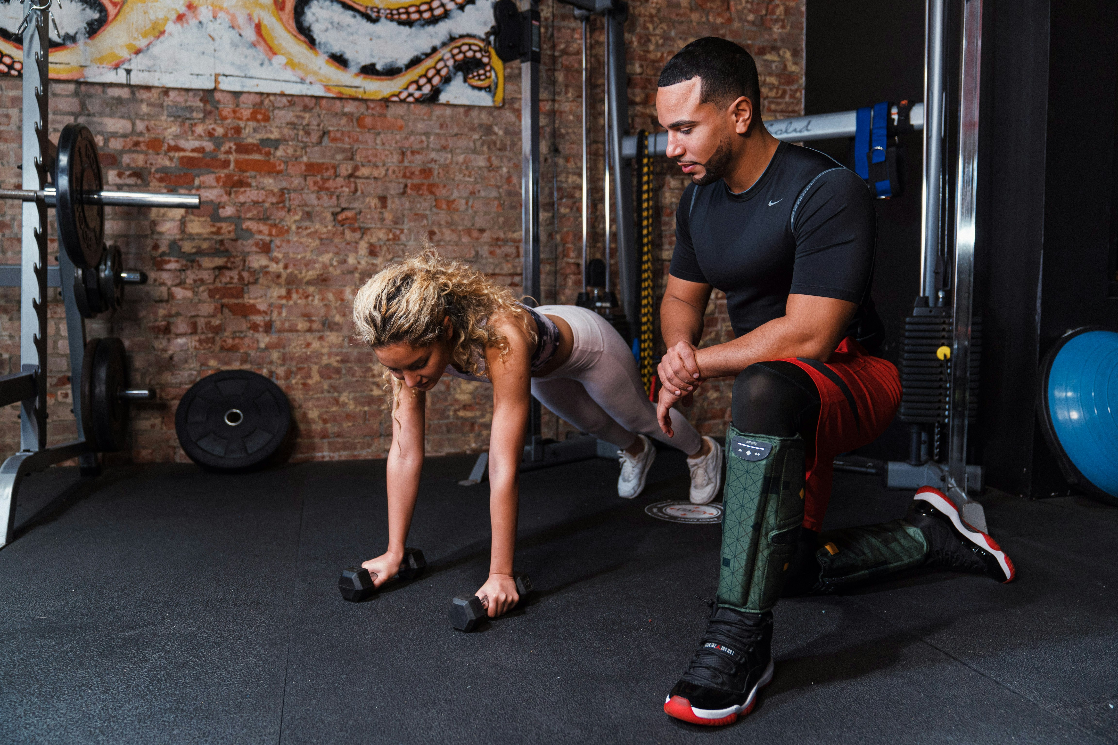 Un hombre ayudando a otro hombre a hacer flexiones