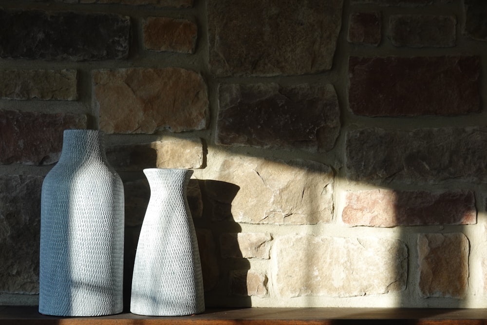 a couple of vases sit in front of a brick wall