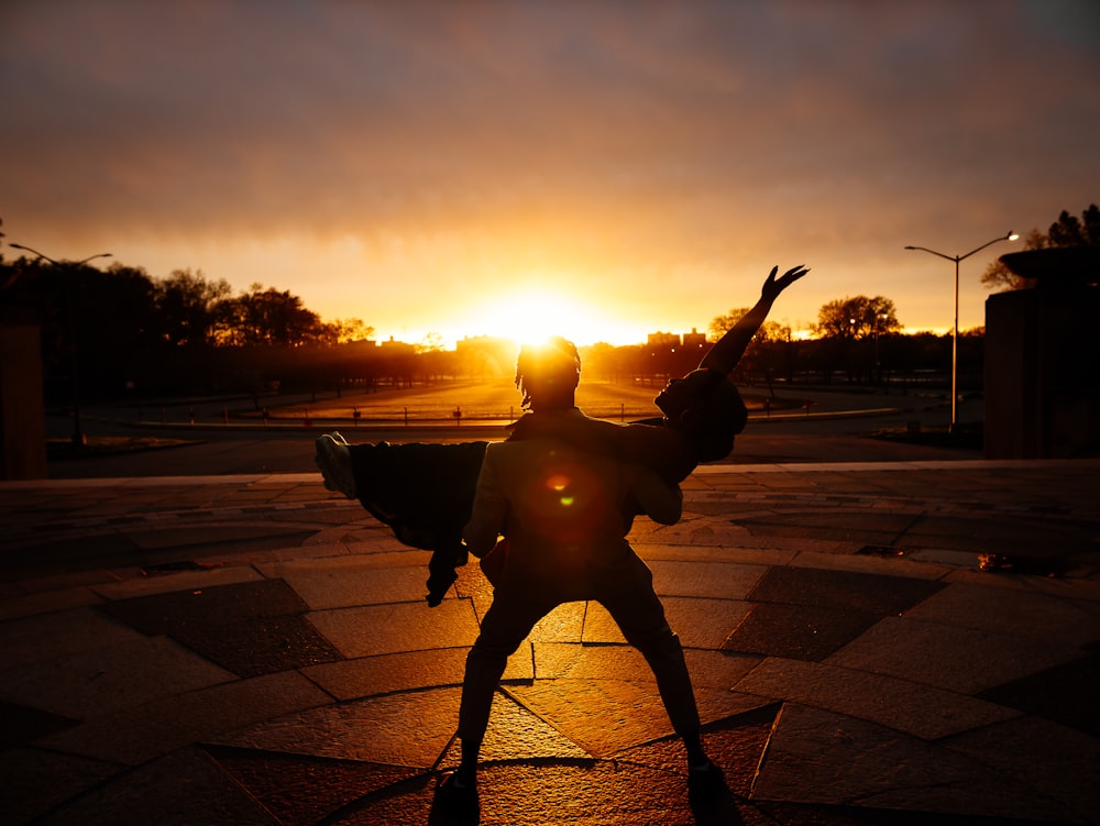 a statue of a person holding a gun in front of a sunset