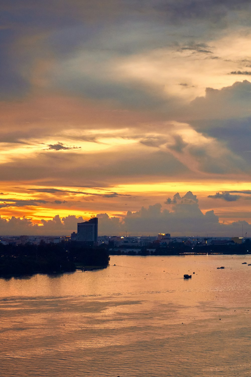 a body of water with buildings and a sunset in the background