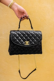 a hand holding a black purse