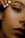A close-up of a woman's face focusing on the eye area, showcasing detailed makeup with bold eyeliner and well-groomed eyebrows. Her lips are visible in the bottom right, with a natural-looking lipstick. A hand with neatly manicured white nails is positioned near her forehead.